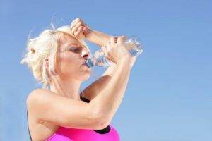Woman with water bottle feels the heat of summer
