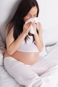 Sneezing pregnant woman on the bed